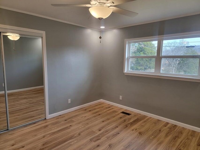 unfurnished room featuring visible vents, baseboards, ornamental molding, and wood finished floors