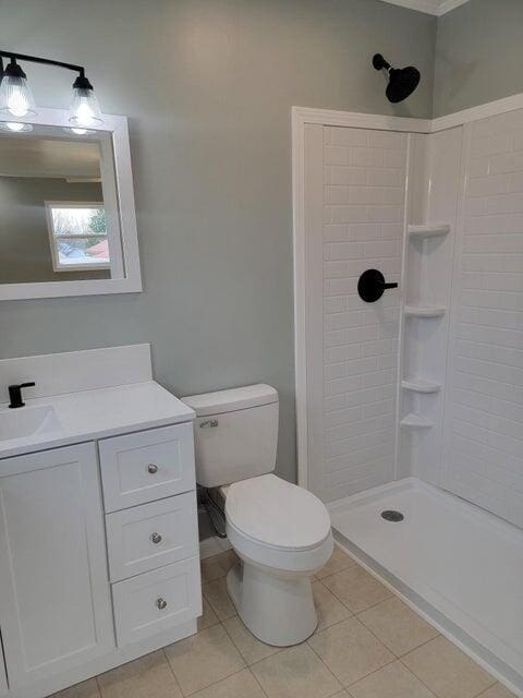 bathroom featuring a tile shower, tile patterned flooring, and toilet