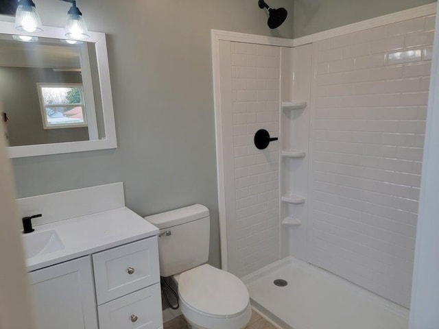 full bath featuring toilet, tiled shower, and vanity
