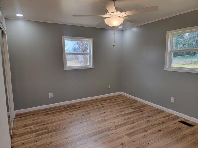 spare room featuring plenty of natural light, visible vents, crown molding, and wood finished floors