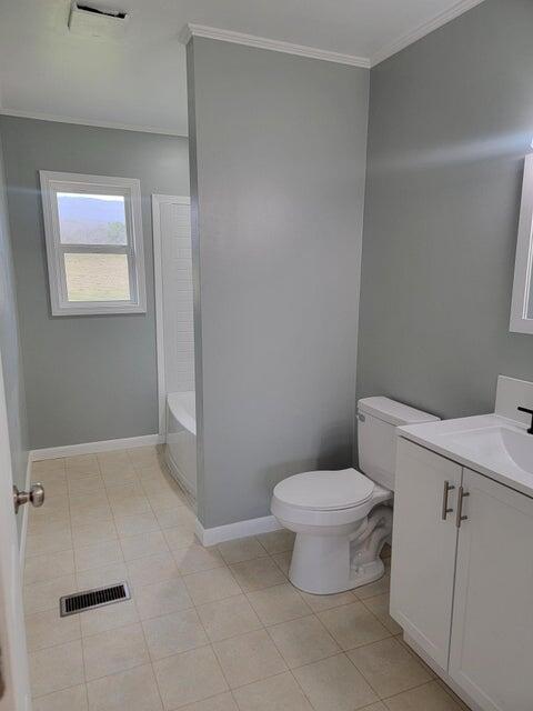 bathroom with visible vents, ornamental molding, toilet, a tub to relax in, and vanity