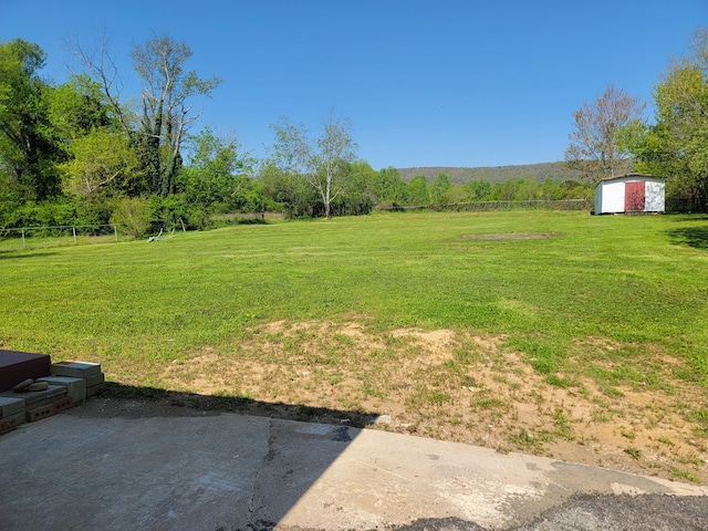 view of yard featuring a storage shed, a detached garage, fence, and an outdoor structure