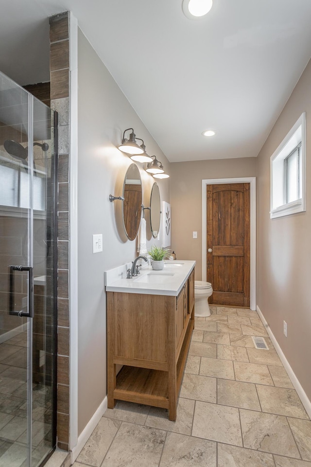 bathroom featuring vanity, a shower with door, and toilet