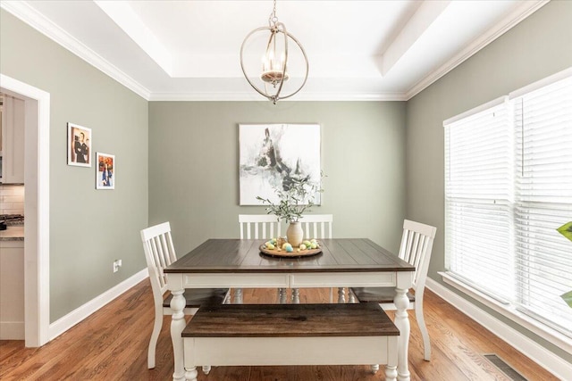 dining room with light wood-type flooring, a raised ceiling, and visible vents