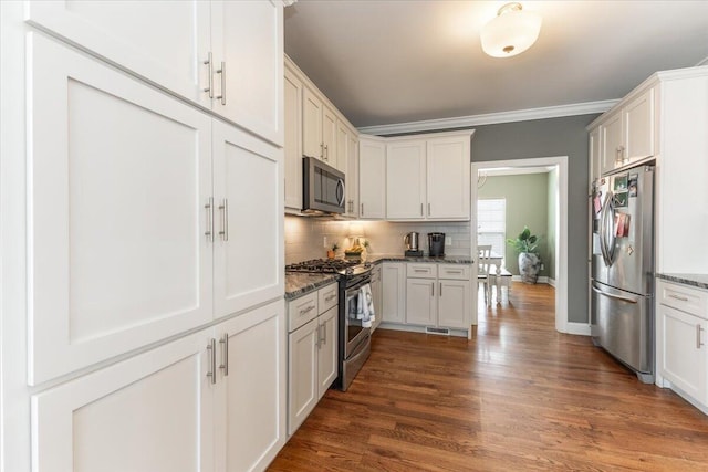 kitchen with stone countertops, appliances with stainless steel finishes, dark wood-style flooring, crown molding, and backsplash