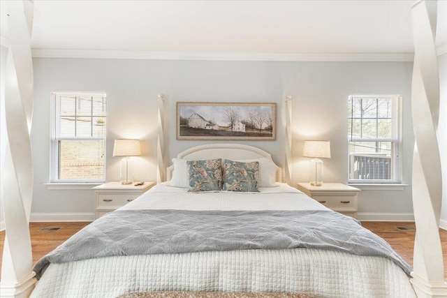 bedroom with ornamental molding, wood finished floors, and baseboards