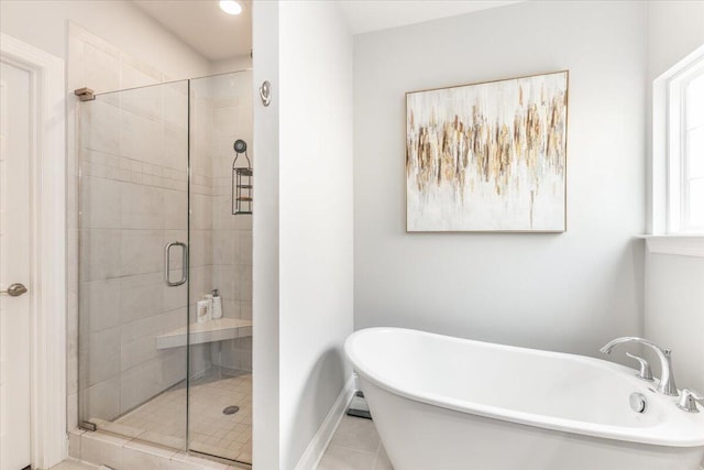 bathroom featuring a stall shower, a soaking tub, tile patterned flooring, and baseboards