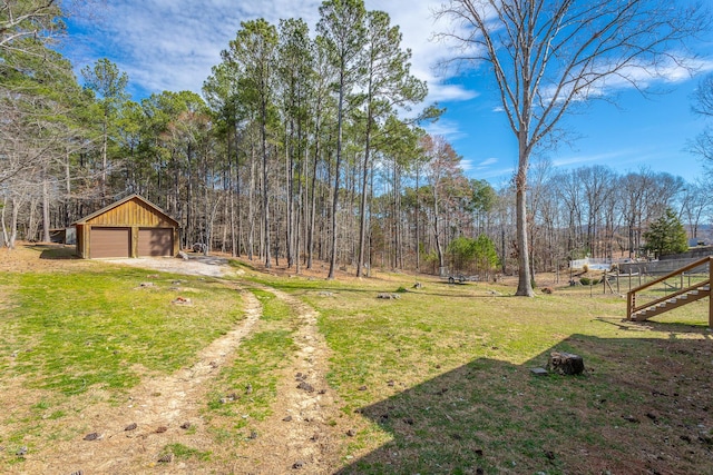 view of yard with a garage, driveway, and an outdoor structure