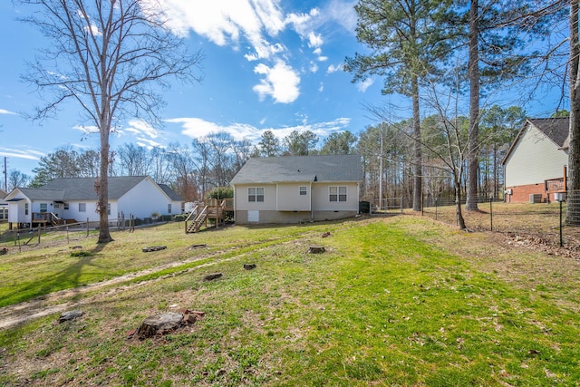 rear view of property with a yard, stairway, crawl space, and fence