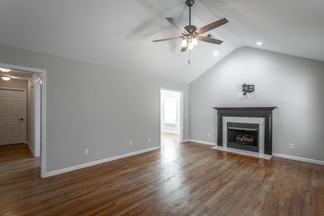 unfurnished living room with baseboards, wood finished floors, a high end fireplace, and vaulted ceiling