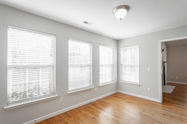 empty room with visible vents, baseboards, and light wood finished floors