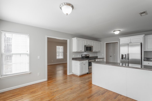 kitchen featuring baseboards, appliances with stainless steel finishes, light wood-style flooring, and white cabinetry