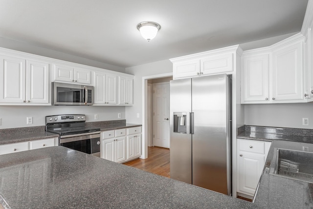 kitchen featuring light wood finished floors, white cabinets, and appliances with stainless steel finishes