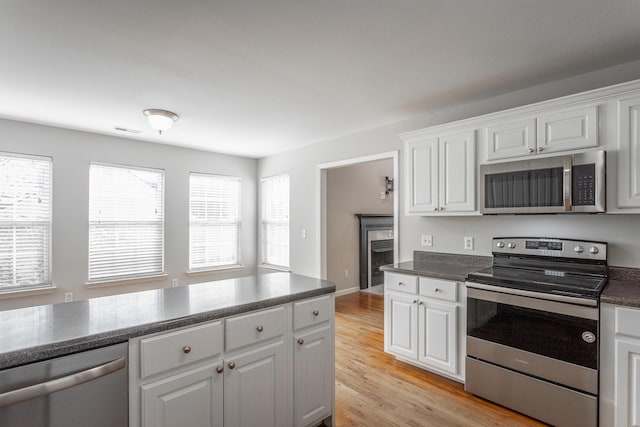 kitchen with visible vents, light wood finished floors, white cabinets, appliances with stainless steel finishes, and dark countertops
