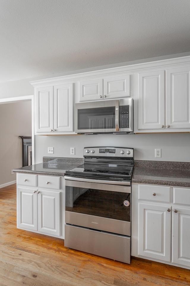 kitchen featuring dark countertops, white cabinets, and appliances with stainless steel finishes