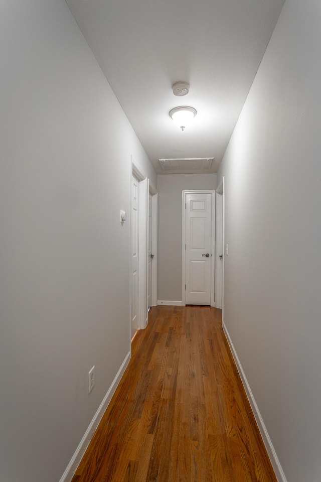 corridor with baseboards and wood finished floors