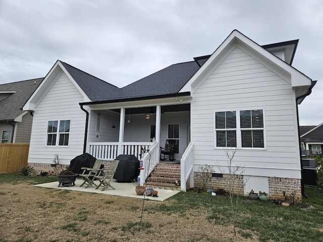 rear view of property featuring a patio area, a porch, a yard, and an outdoor fire pit