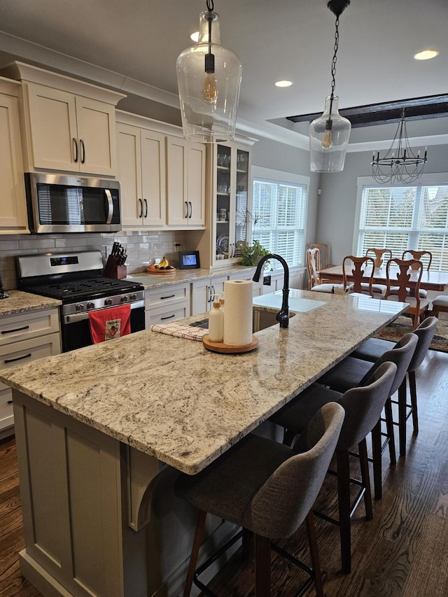 kitchen featuring appliances with stainless steel finishes, a large island, a kitchen breakfast bar, dark hardwood / wood-style flooring, and ornamental molding