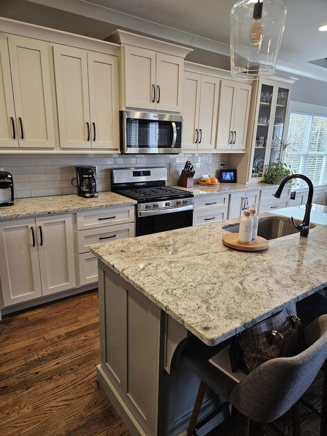 kitchen with sink, light stone counters, appliances with stainless steel finishes, a kitchen bar, and dark hardwood / wood-style floors