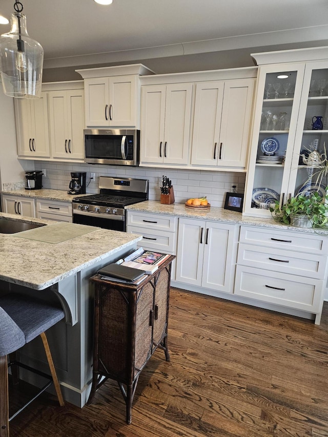 kitchen featuring hanging light fixtures, white cabinetry, stainless steel appliances, and dark hardwood / wood-style floors