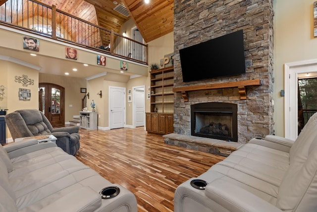 living room featuring hardwood / wood-style flooring, high vaulted ceiling, a stone fireplace, wooden ceiling, and french doors