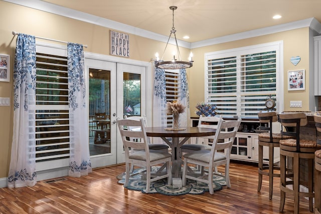 dining space featuring ornamental molding, hardwood / wood-style floors, an inviting chandelier, and french doors