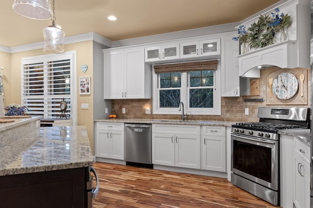 kitchen featuring white cabinetry, stainless steel appliances, decorative light fixtures, and sink