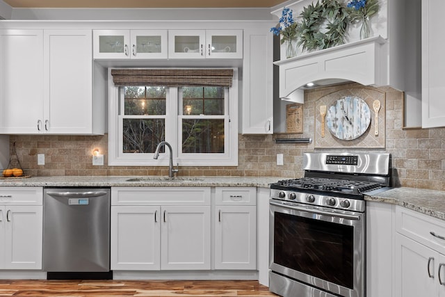 kitchen with appliances with stainless steel finishes, light stone countertops, sink, and white cabinets