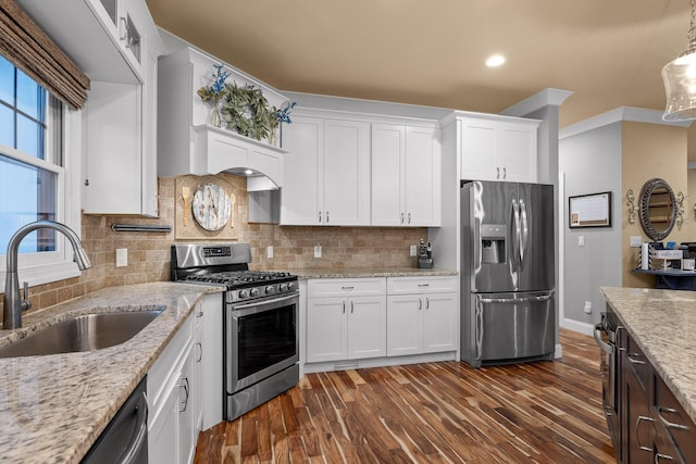 kitchen with hanging light fixtures, white cabinetry, appliances with stainless steel finishes, and sink