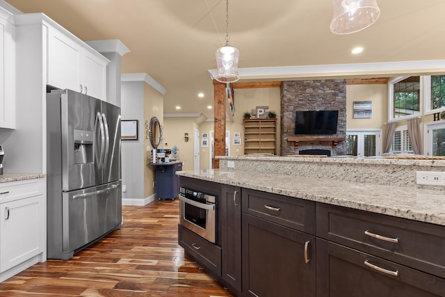 kitchen with appliances with stainless steel finishes, white cabinetry, hanging light fixtures, light stone counters, and dark hardwood / wood-style flooring