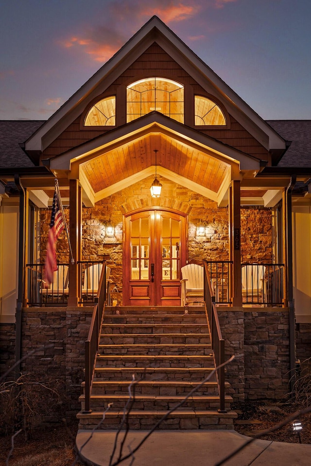 exterior entry at dusk featuring french doors and covered porch