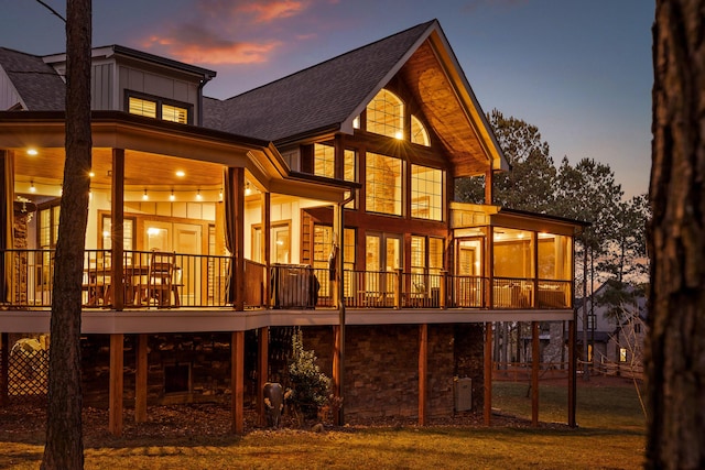 back house at dusk featuring a sunroom