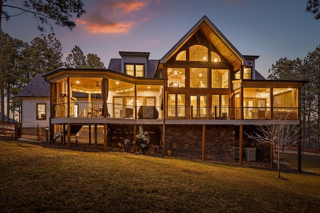 back house at dusk with central AC unit, a yard, a deck, and ceiling fan