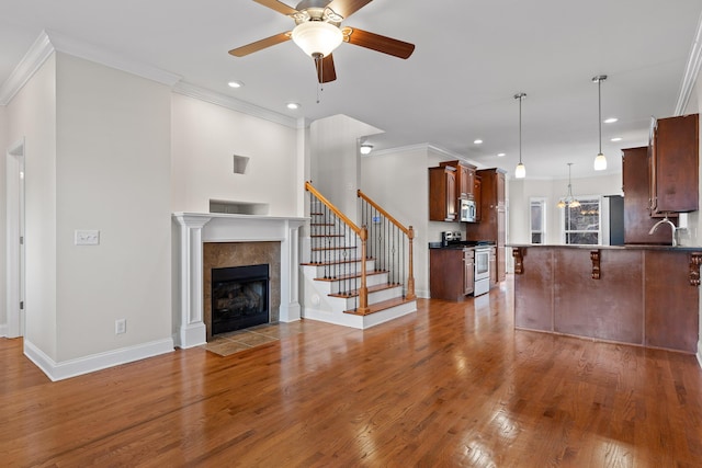 unfurnished living room with ceiling fan, ornamental molding, a fireplace, and hardwood / wood-style floors