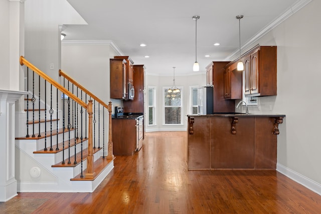 kitchen with dark hardwood / wood-style flooring, hanging light fixtures, ornamental molding, kitchen peninsula, and stainless steel appliances