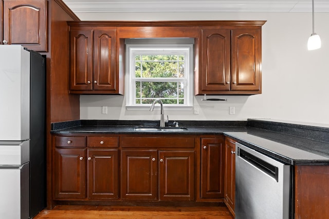 kitchen featuring pendant lighting, sink, crown molding, stainless steel appliances, and dark stone counters