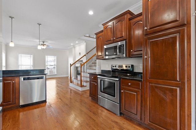 kitchen with crown molding, hanging light fixtures, appliances with stainless steel finishes, ceiling fan, and hardwood / wood-style floors