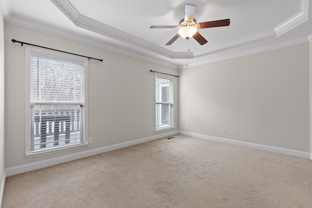 empty room with crown molding, light colored carpet, a tray ceiling, and ceiling fan