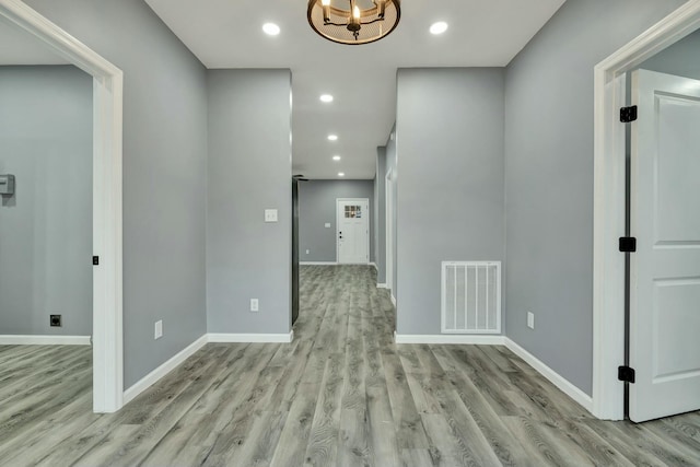 hall with an inviting chandelier and light hardwood / wood-style floors