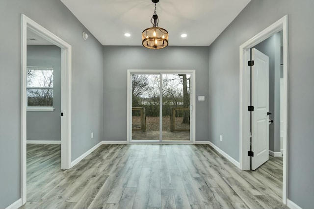 spare room featuring a chandelier and light hardwood / wood-style floors