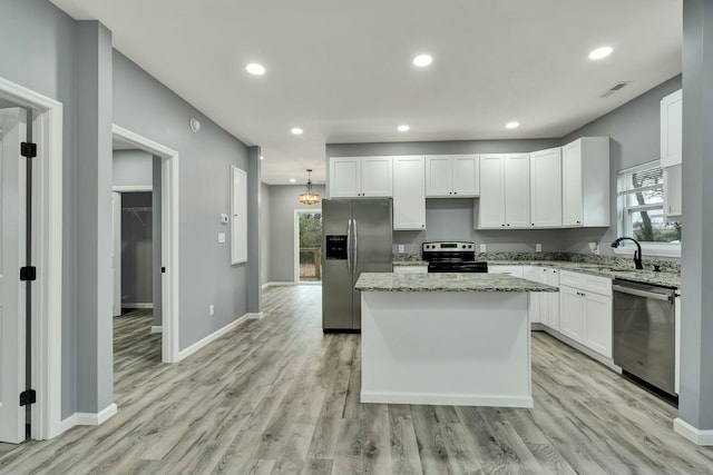 kitchen featuring sink, stainless steel appliances, a center island, and white cabinets