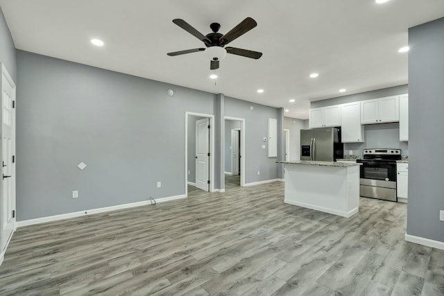 kitchen with light stone countertops, stainless steel appliances, white cabinets, and a kitchen island