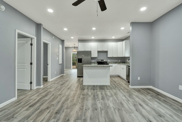 kitchen featuring stainless steel appliances, light hardwood / wood-style floors, white cabinets, and a kitchen island