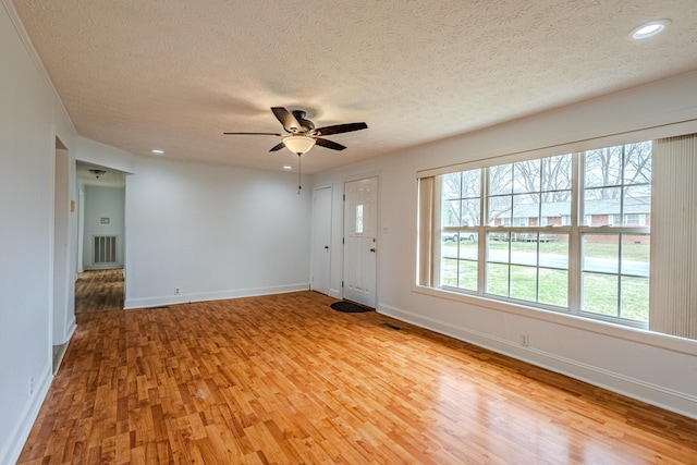 empty room featuring a textured ceiling, light hardwood / wood-style flooring, and ceiling fan