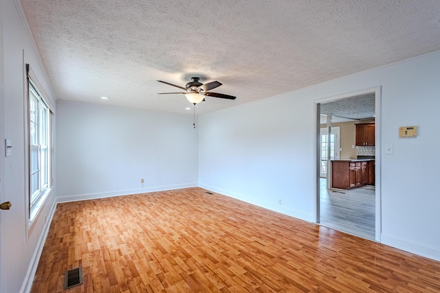 empty room featuring ceiling fan, a textured ceiling, and light wood-type flooring