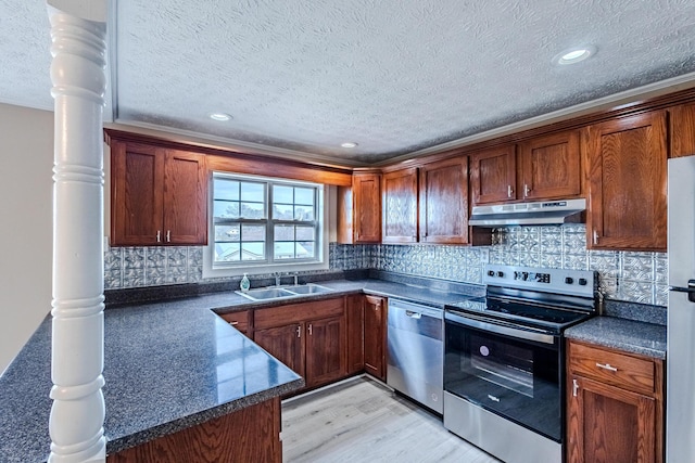 kitchen featuring stainless steel appliances, tasteful backsplash, sink, and decorative columns