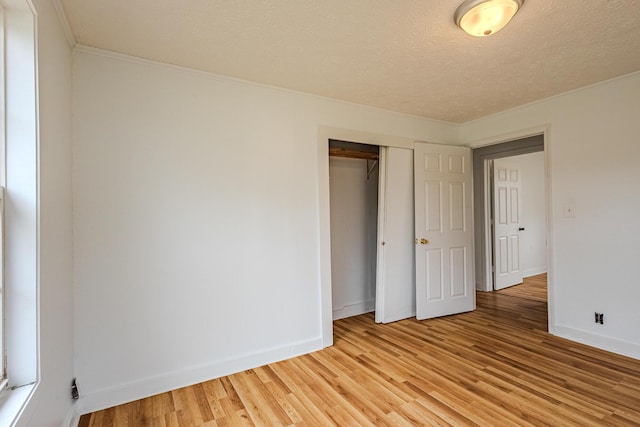 unfurnished bedroom with light hardwood / wood-style flooring, a closet, and a textured ceiling