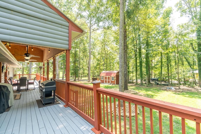 deck featuring a grill, a lawn, ceiling fan, and a shed