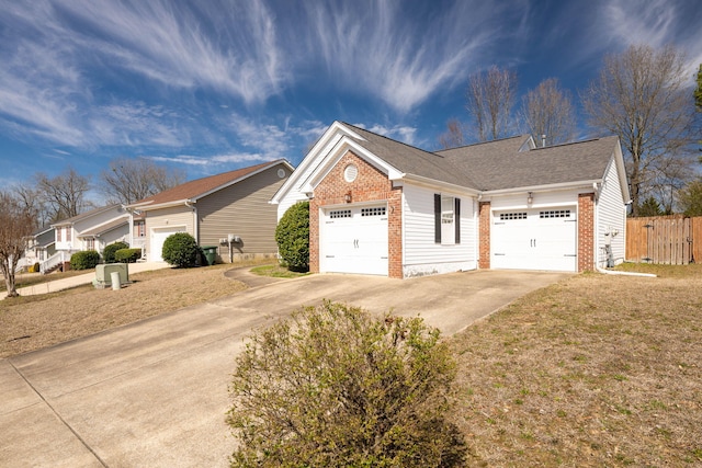 view of side of property with a garage, concrete driveway, brick siding, and fence