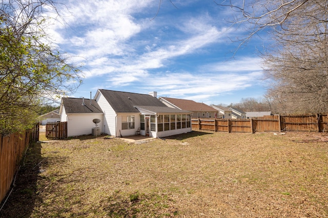 back of house featuring a chimney, a fenced backyard, and a sunroom